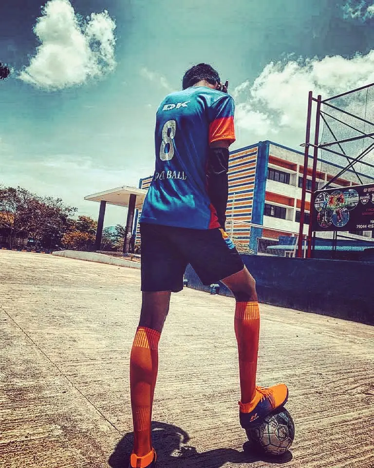 Rahul Dhileep Kumar from behind in a number 8 jersey, foot on a football