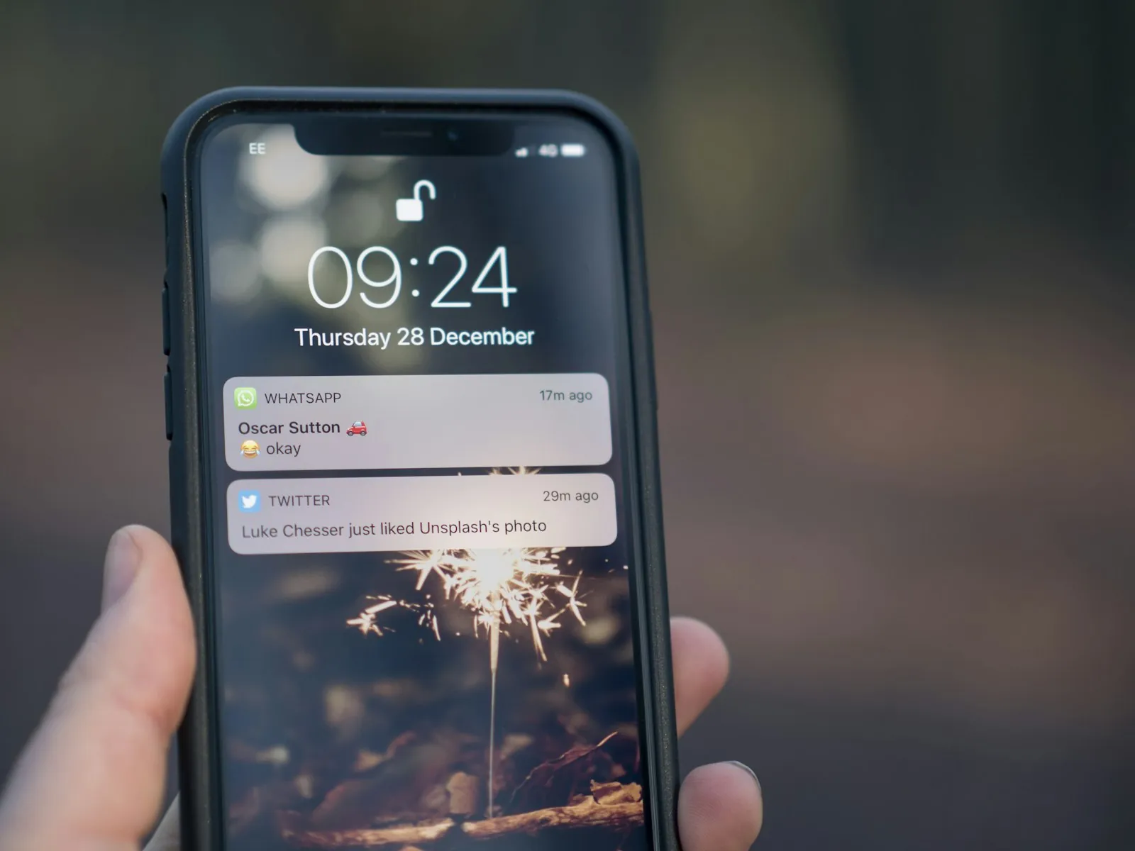 A hand holding a smartphone showing notifications on the lock screen