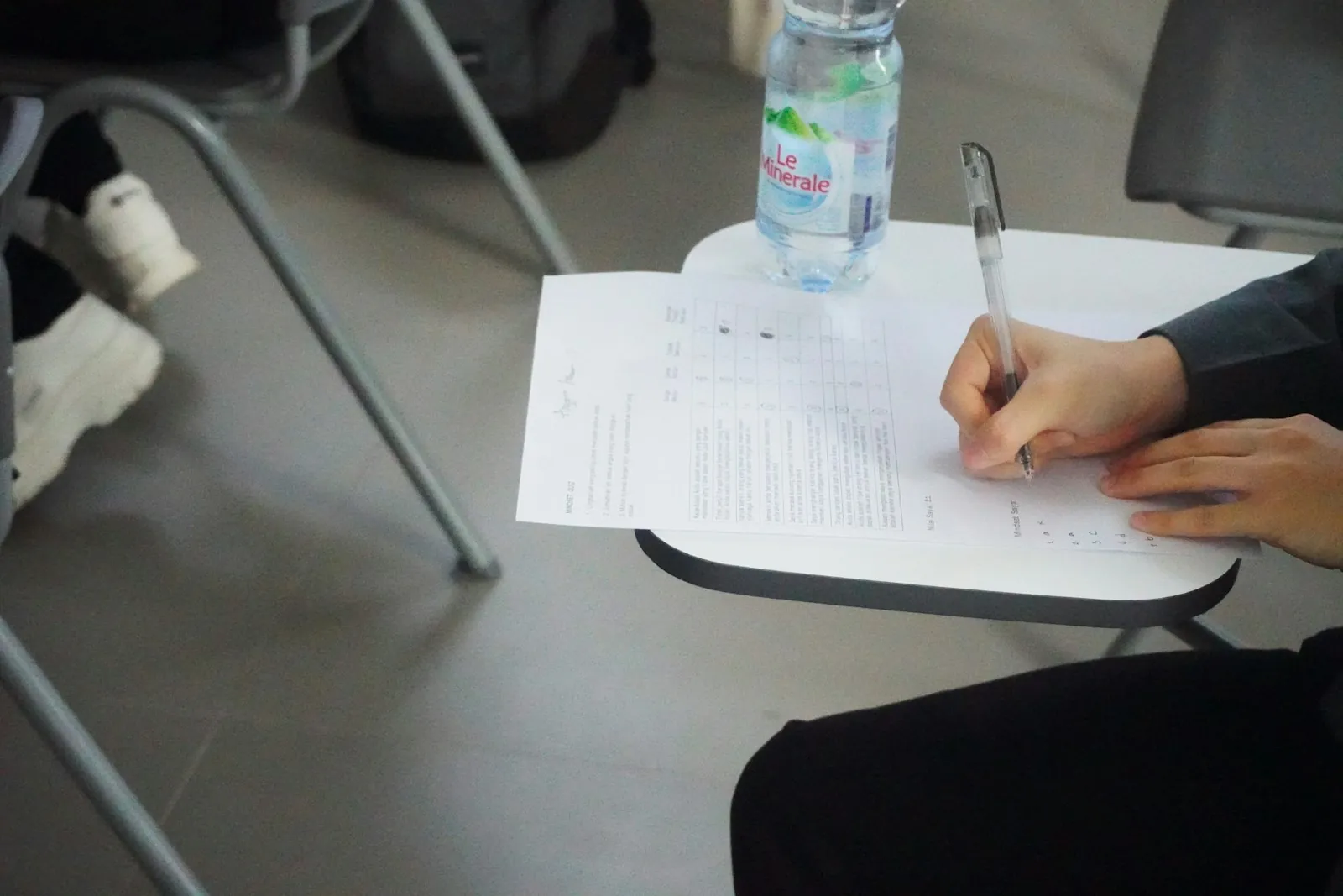A person writing notes on a sheet of paper at a desk