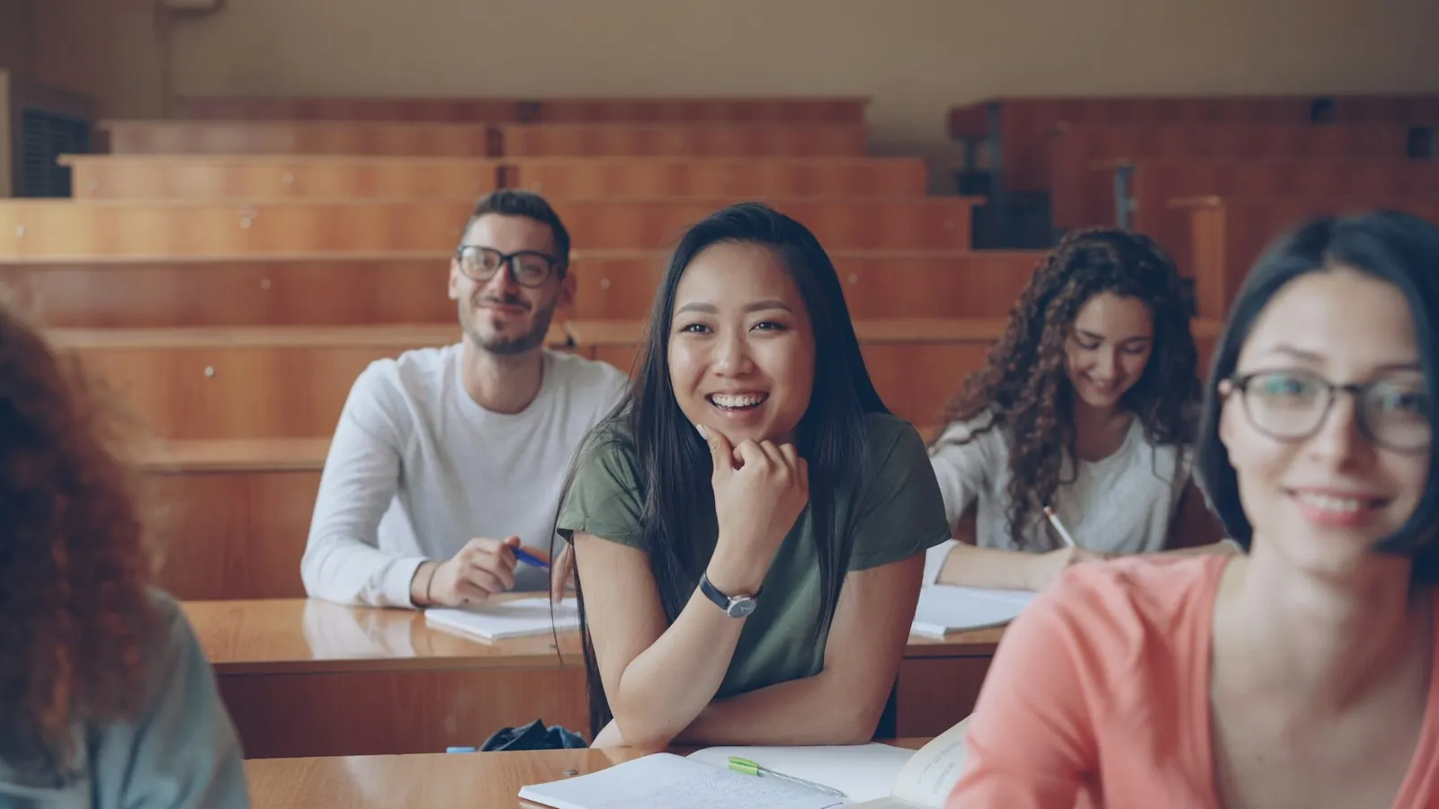 Students smiling in a college lecture hall during a class