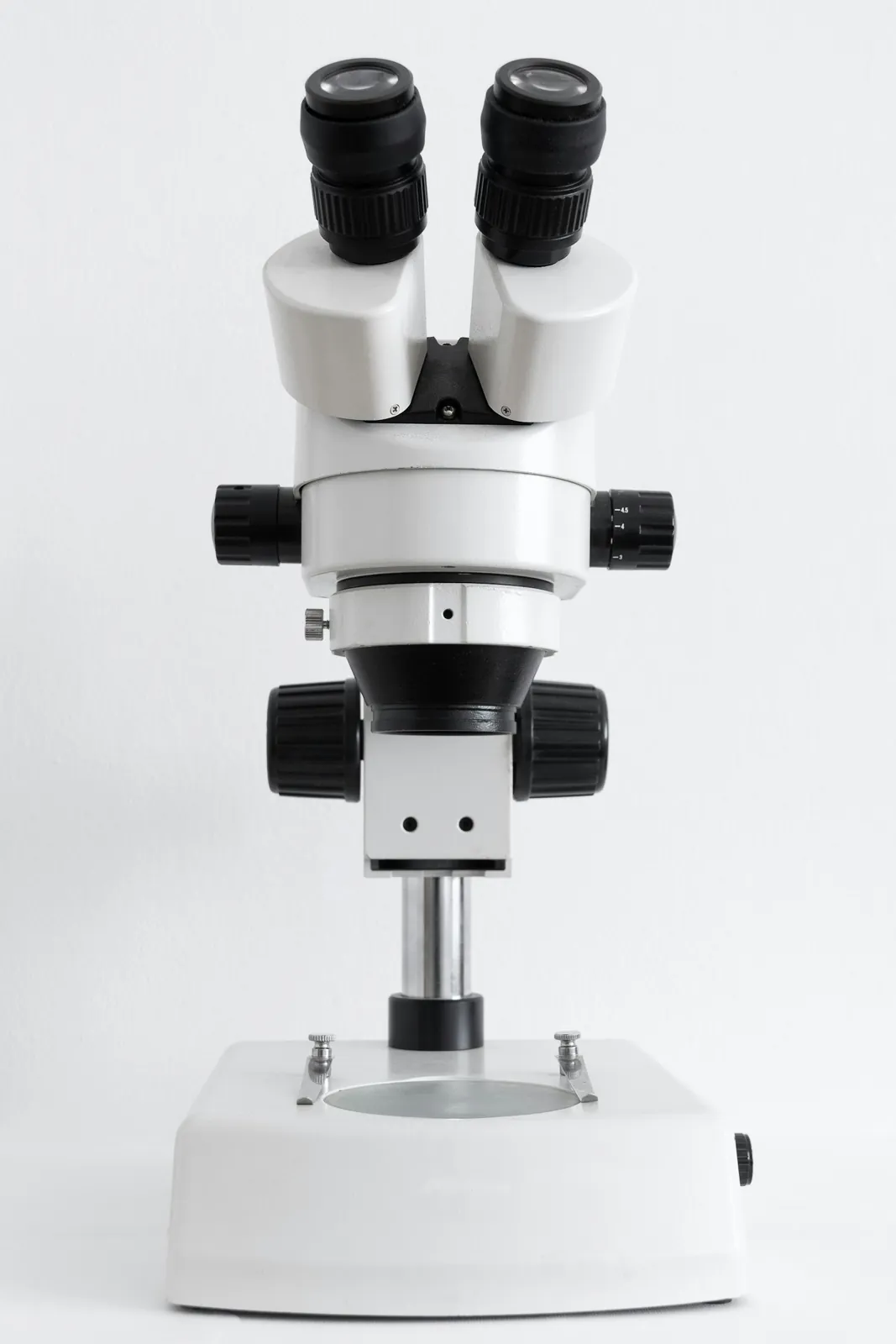 A white microscope on a plain white surface, the biology half of a bio-maths stream