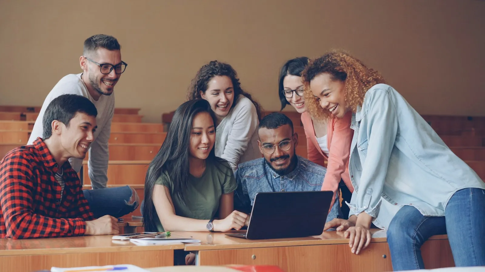 Students gathered around a laptop, comparing AI coding assistants on a shared task