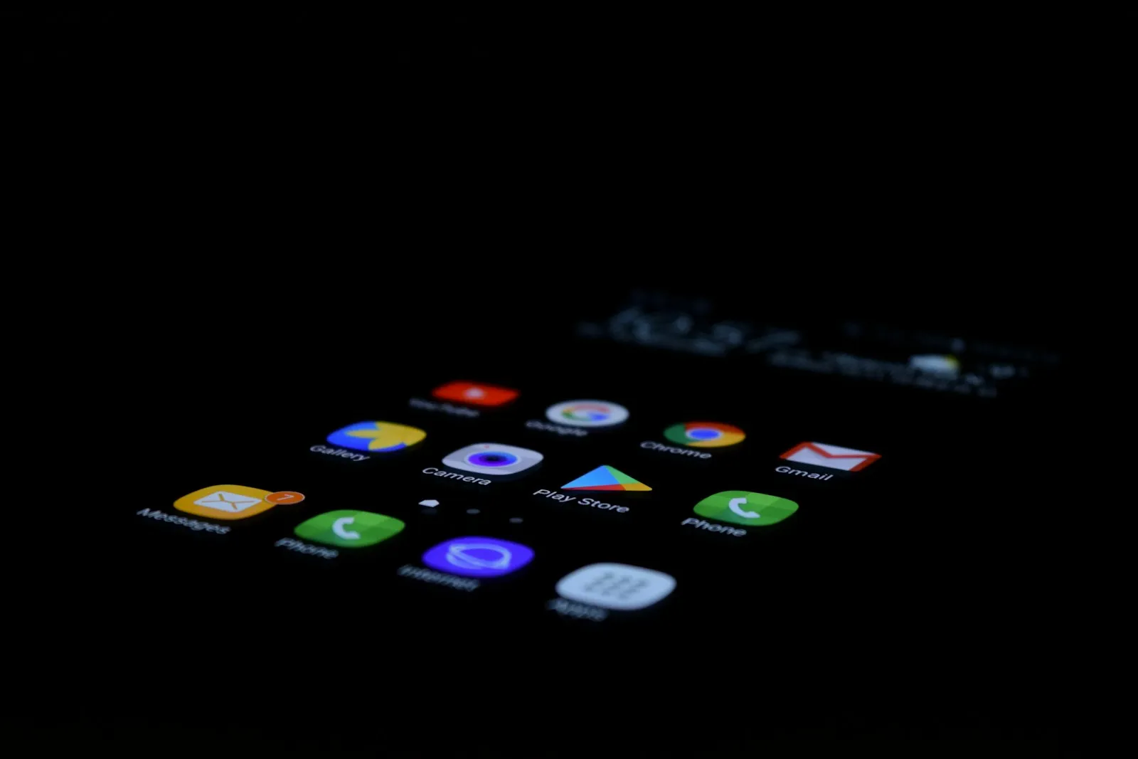 A smartphone screen glowing in a dark room, showing app icons including the phone app