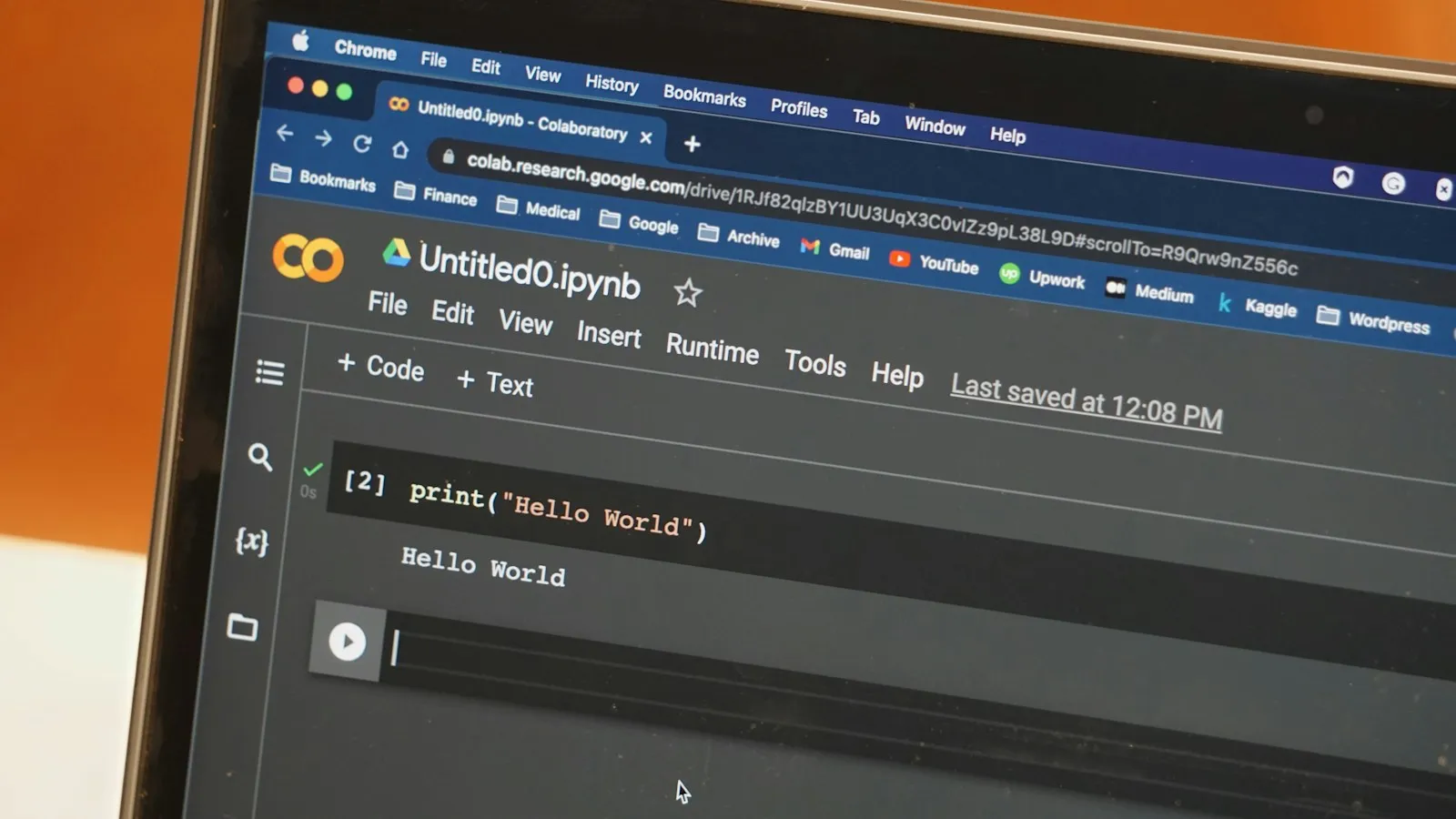 A laptop showing a Google Colab notebook that has just printed Hello World