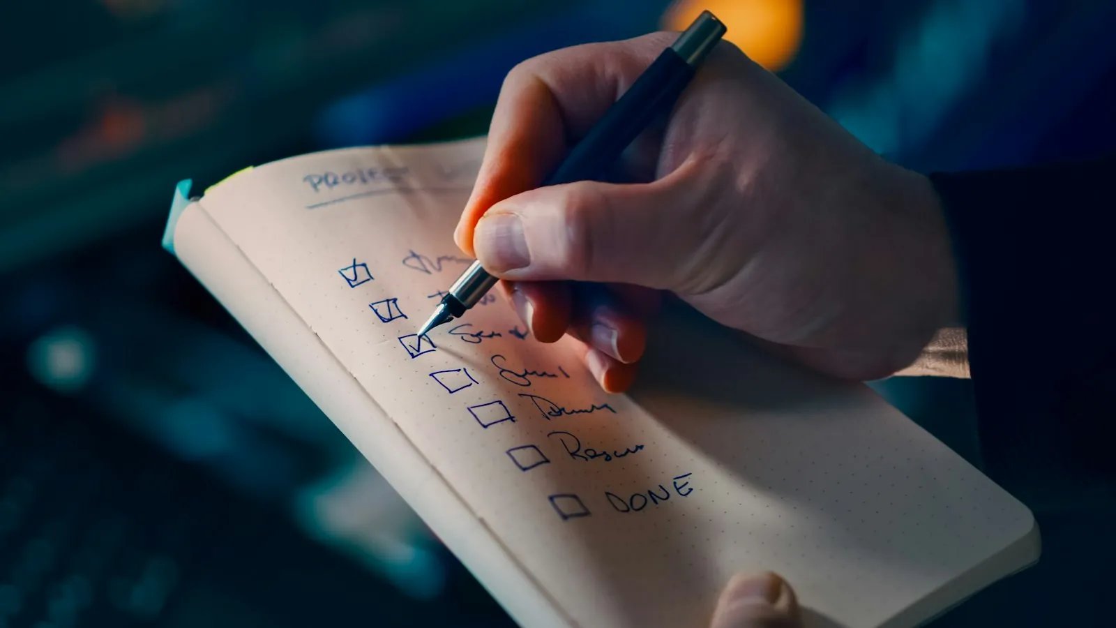A hand ticking items off a deployment checklist in a notebook