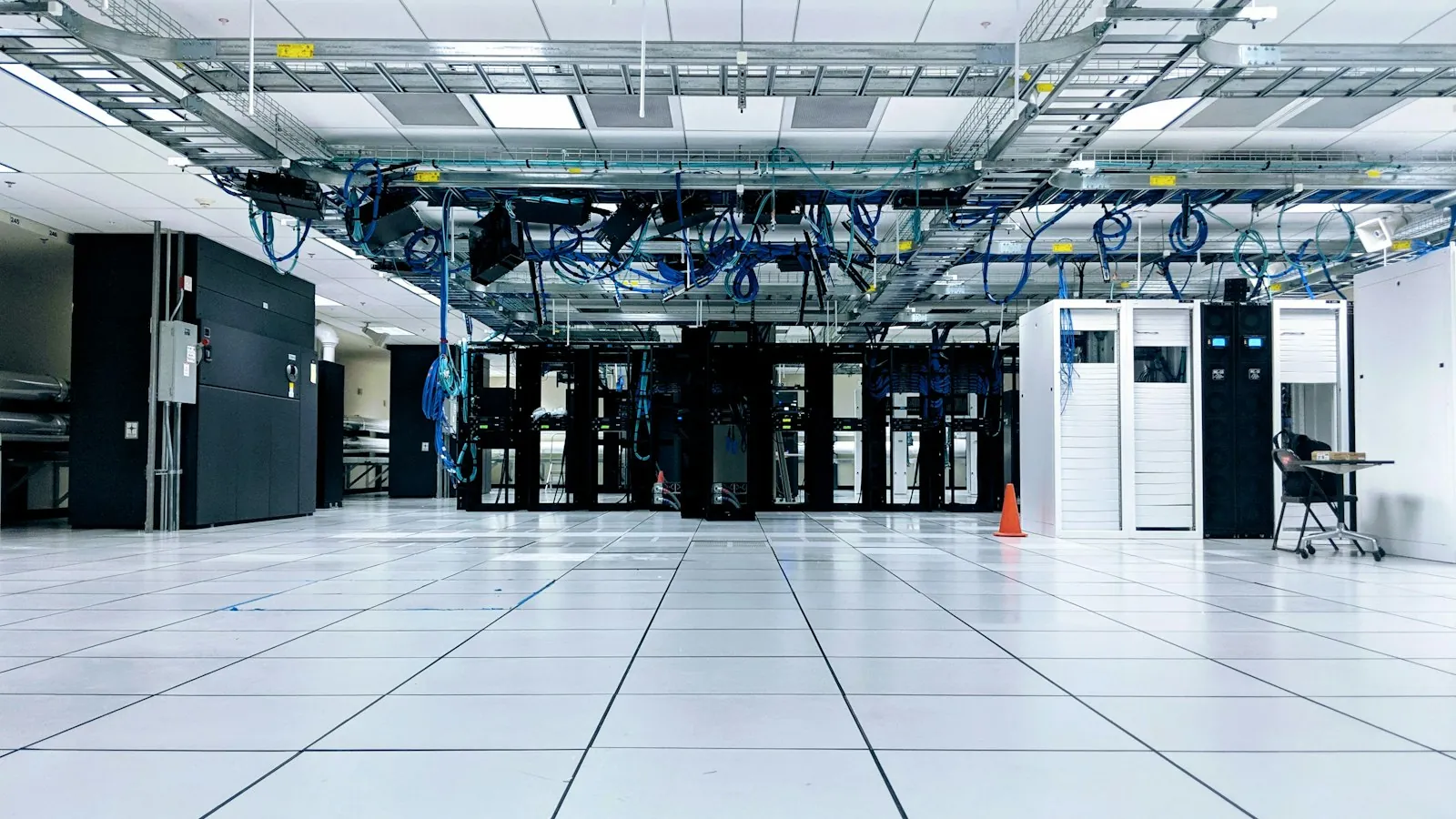 A server room with rows of network cabinets under blue cables