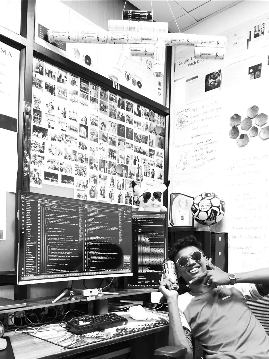 Rahul at his desk, giving a thumbs up with an energy drink