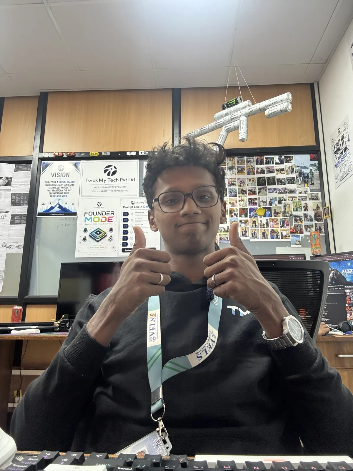 Rahul giving two thumbs up at the TrackMy Tech office, under a chandelier made of Monster cans