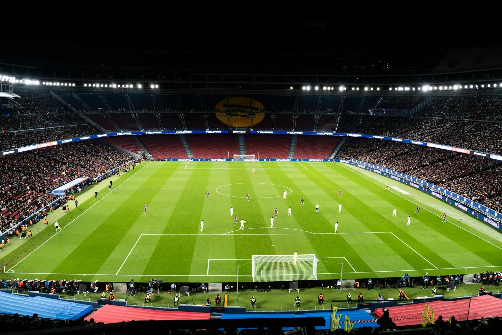 Floodlit football stadium at night with a full crowd watching a match