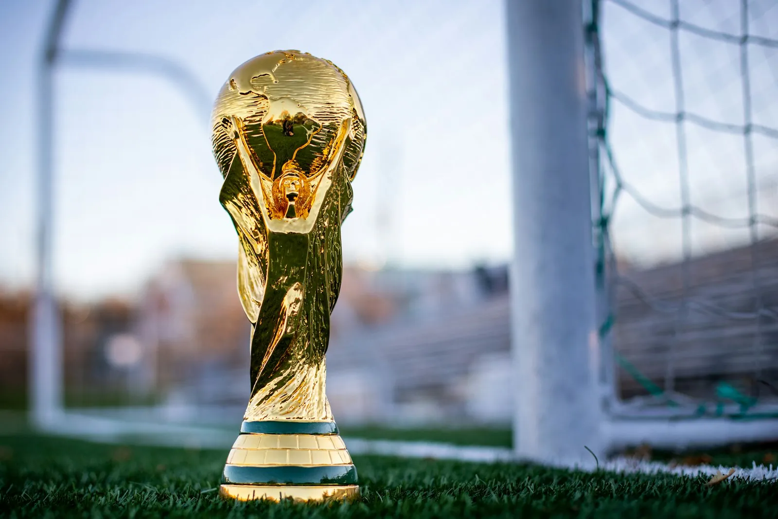 Gold football trophy standing on the grass in front of a goal net