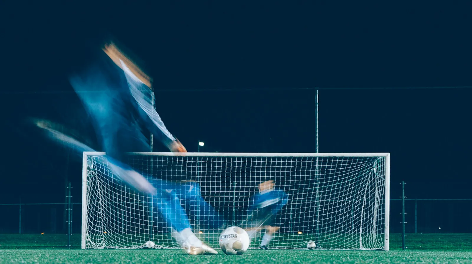 Long-exposure shot of a player striking a penalty, motion blur showing the kick